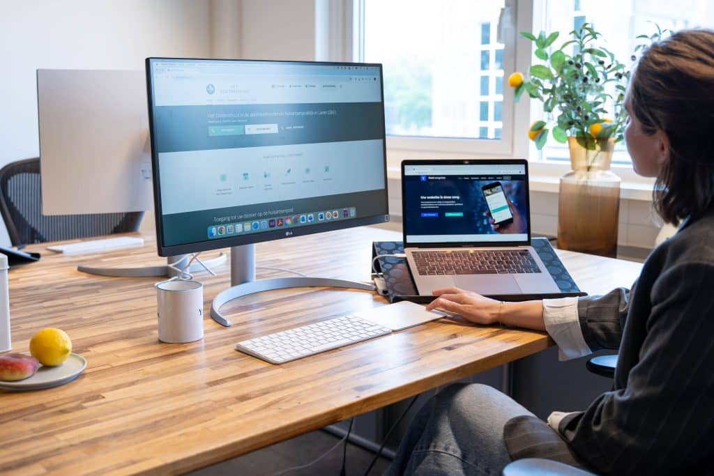 Een vrouw kijkt naar twee schermen met daarop Yard Zorgsites.