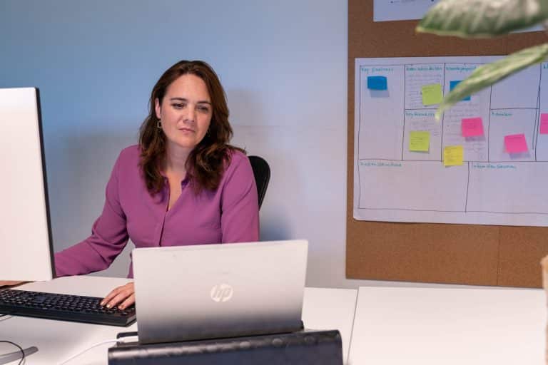 Een vrouw kijkt naar een beeldscherm. Op de achtergrond is een planbord te zien.